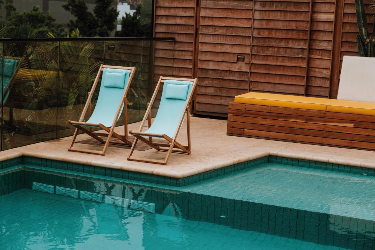 The Click Clack Hotel Medellin Bagian luar foto A pair of deck chairs by a pool